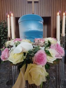 Blaue Utrne vor Blumenstrauß vor Vase mit rosa Rosen